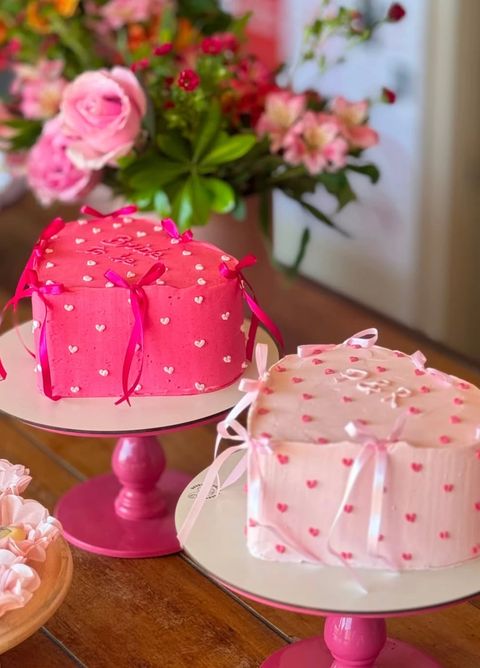 Dois bolos em formato de coração, pink e rosa-claro, com corações de chantilly e laços de fita – Auris Doceria