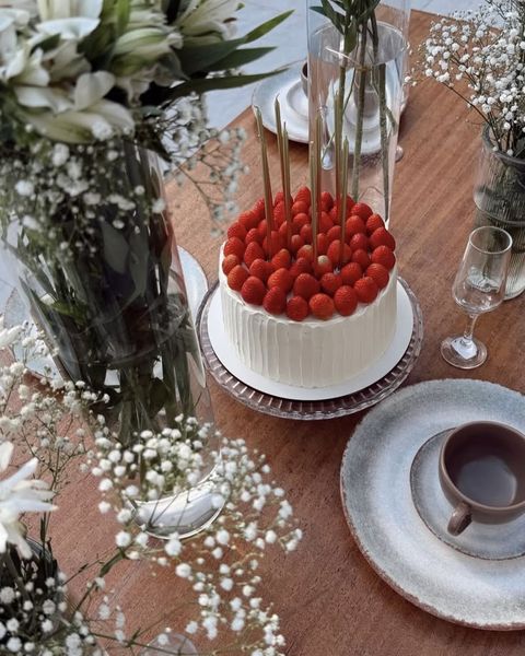 Bolo branco coberto de morangos frescos com velas douradas finas – Auris Doceria
