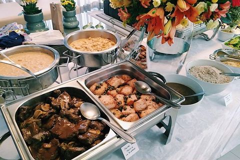 Buffet completo com pratos quentes em mesa decorada com flores