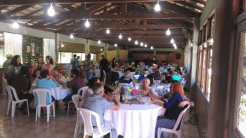 Convidados acomodados em mesas durante um evento com buffet